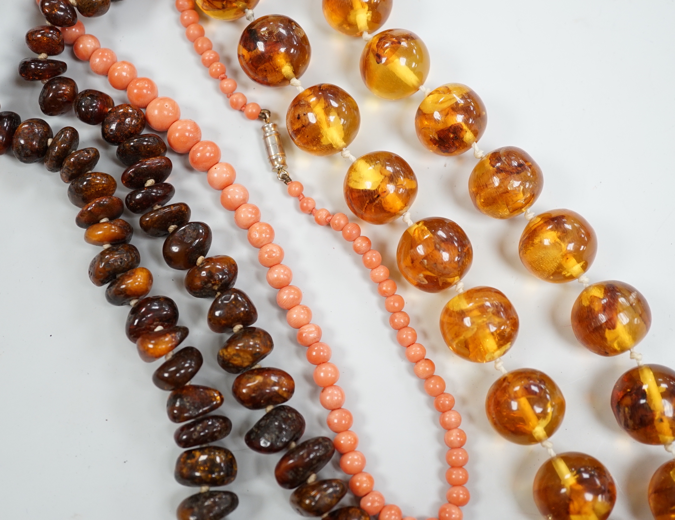 A coral bead necklace, 44cm and two amber bead necklaces.